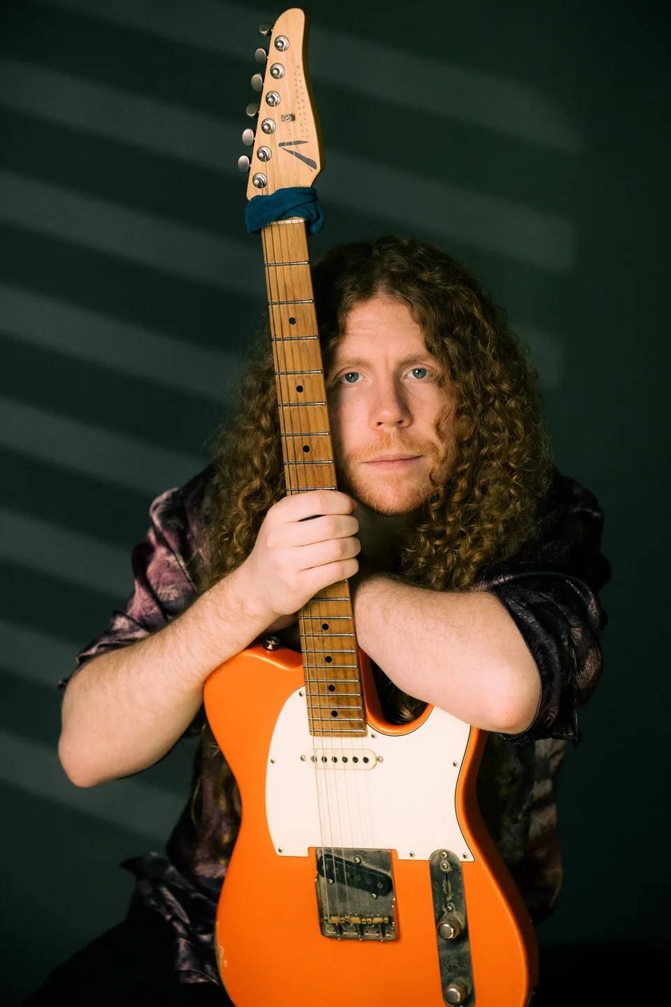 Sean Ashe holding a natural-finish electric guitar beside Sacramento’s yellow Tower Bridge.